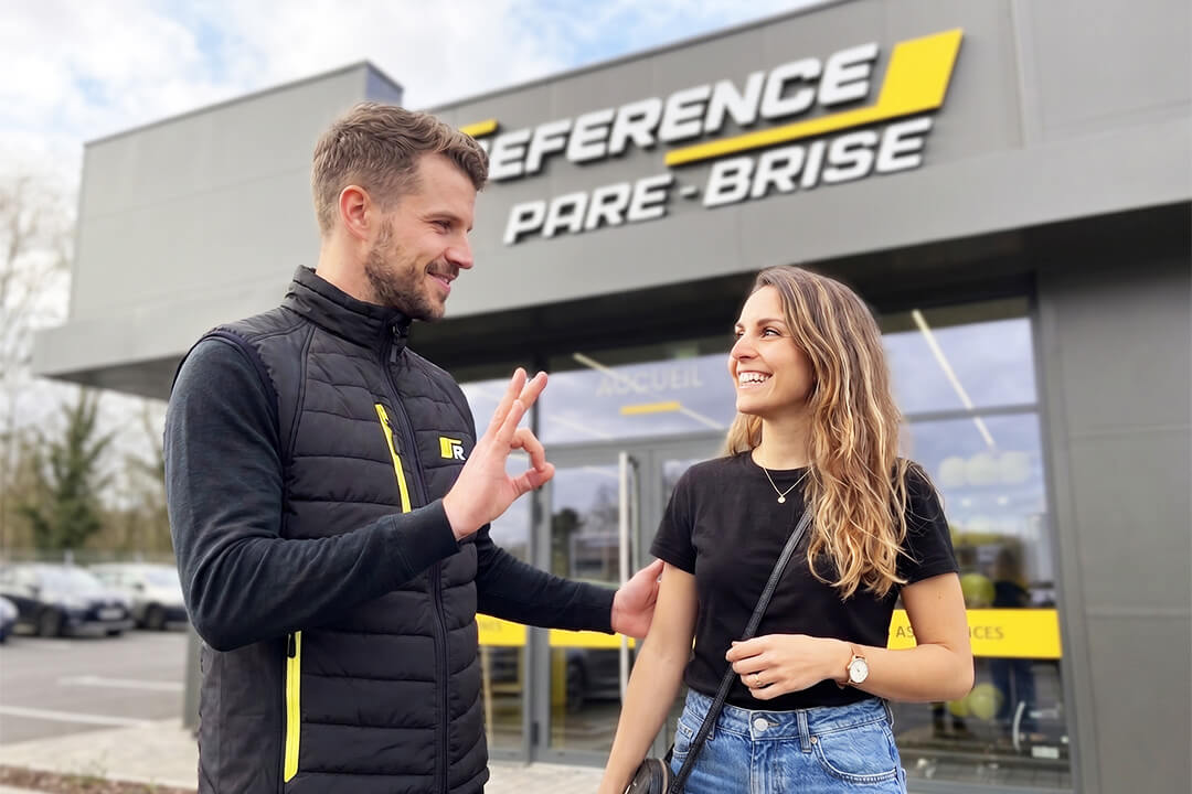 Responsable en discussion avec une cliente devant une agence Reference Pare-Brise